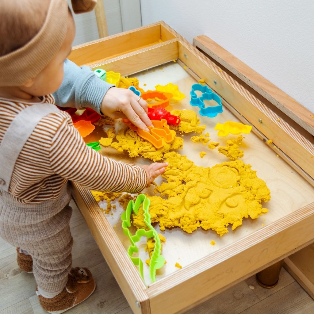 A small child playing quietly with a shape-sorting toy on a soft mat, designed to accompany content discussing signs of autism at 12 months old.