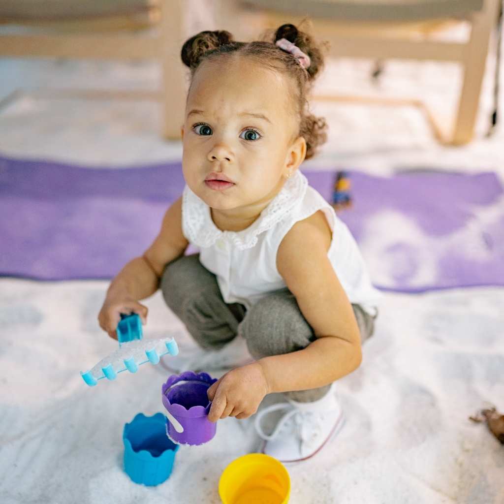 A small child with toys on the floor, used to illustrate early signs of autism at 18 months