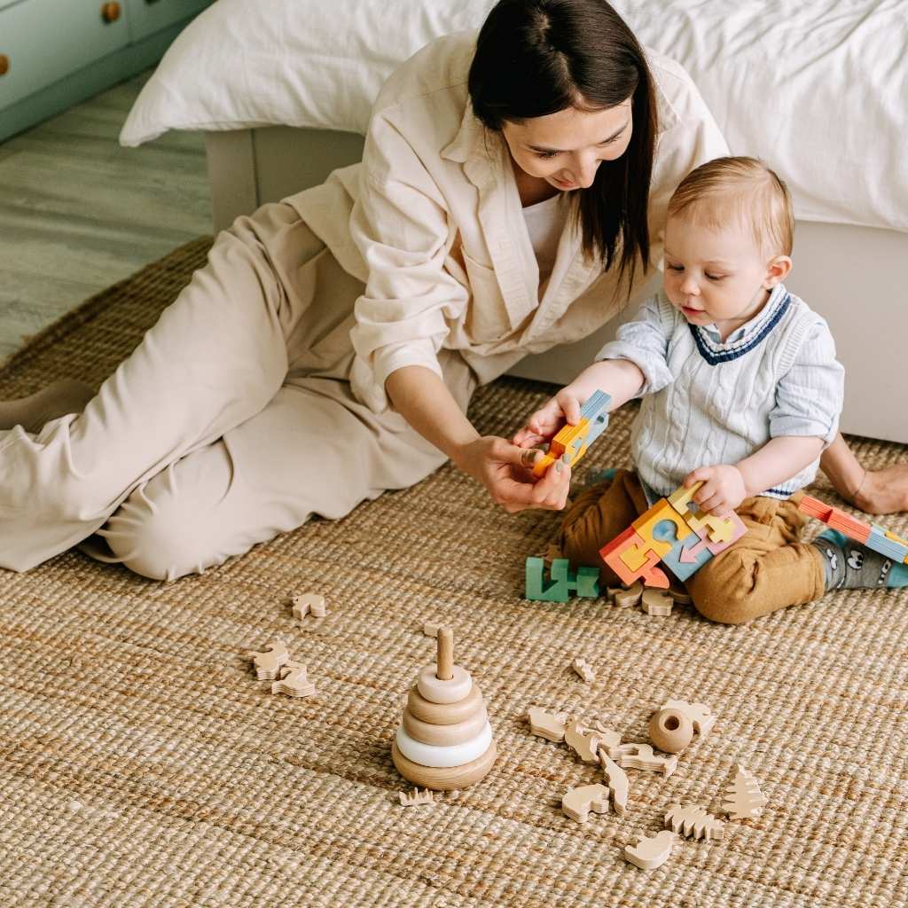 A toddler and an adult, exploring stackers and puzzle toys, supporting an article discussing the topic Is My 18-Month-Old Behind, developmental milestones, and autism.