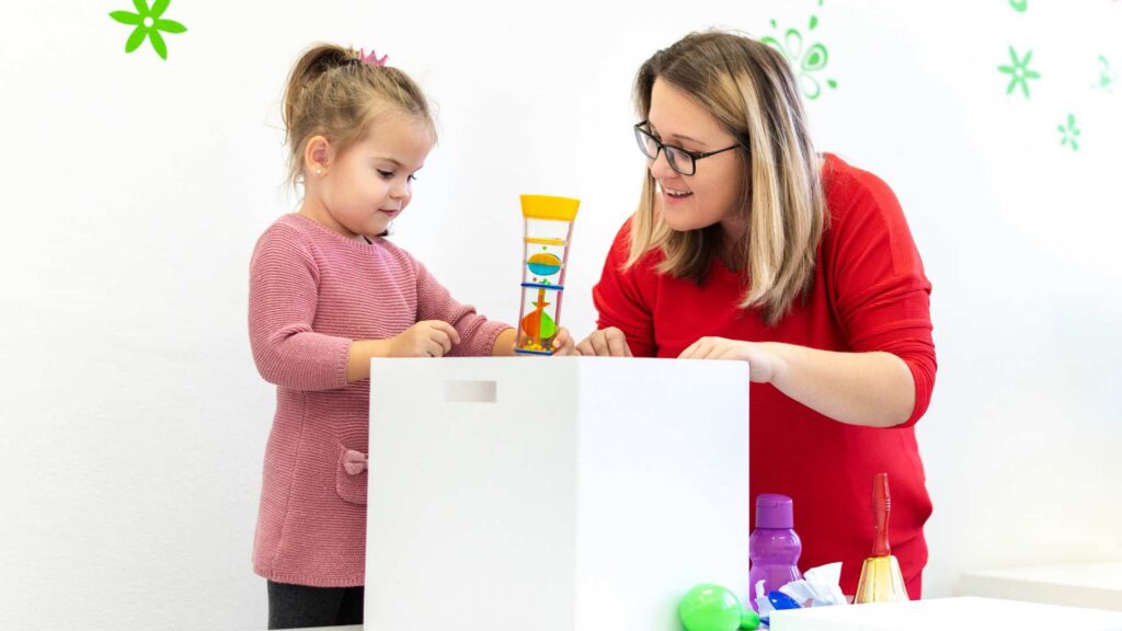 A toddler interacts with RBT using colorful toys, illustrating Signs of ASD at 2 Years Old and the value of early intervention with ABA therapy.