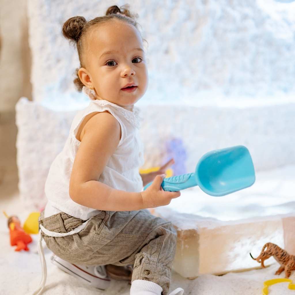 A toddler playing with toys turns toward the person calling them, showing how some children respond right away even when parents worry that a toddler doesn’t respond to their name.