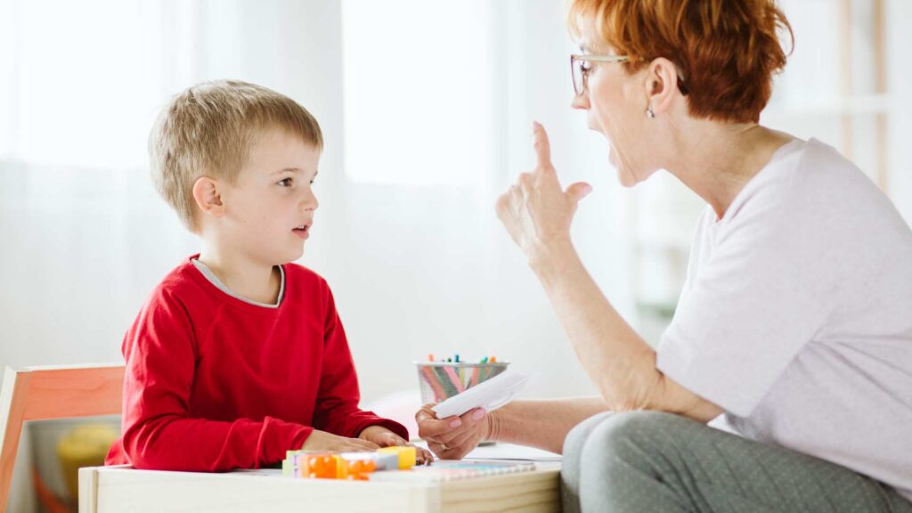 An adult gently working with a child during a learning session, representing early intervention through ABA therapy and awareness of signs of autism at age 3.