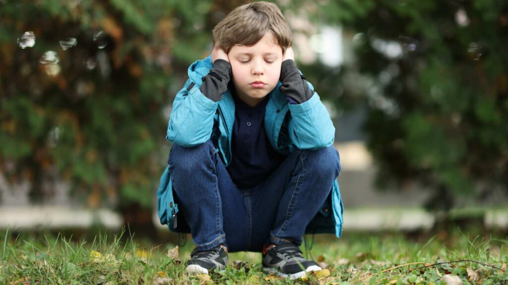 Child experiencing autism masking by hiding natural behaviors in social situations, representing autism social camouflaging