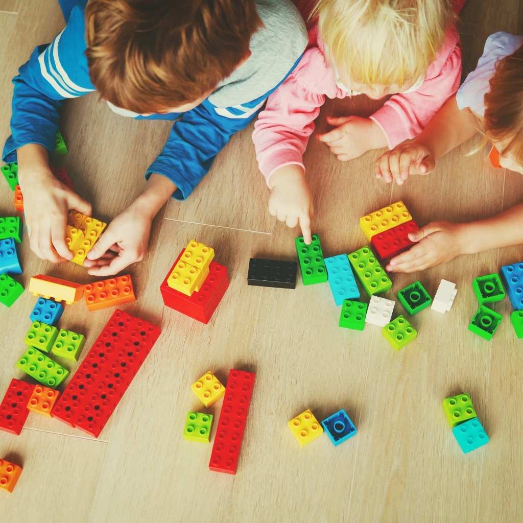Children building with blocks, showing how young children explore repetitive play by stacking, sorting, and rebuilding the same pieces.