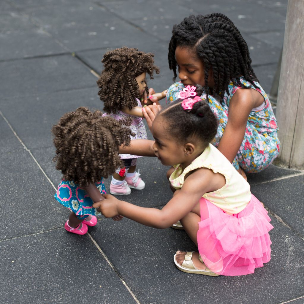 Children engaged in imaginative play with dolls outside