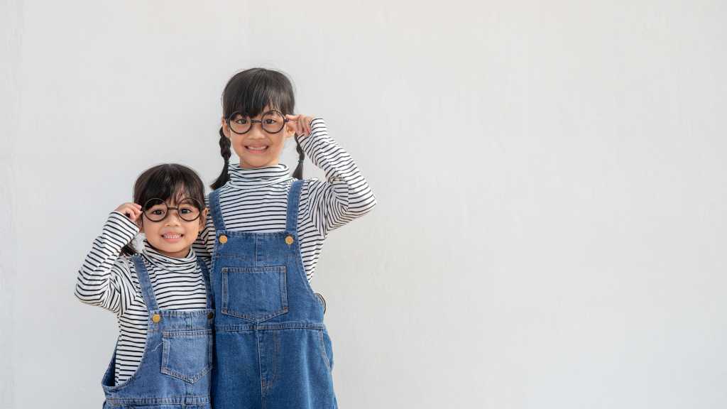 Two young siblings smiling together — supporting children with a sibling with autism.