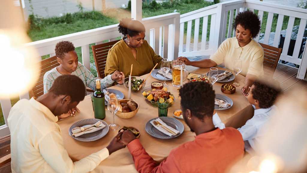Holidays with Autism: 5 Ways of Creating A Joyful Thanksgiving 2 Family holding hands at Thanksgiving dinner, representing calm connection and strategies to navigate autism during the holidays.