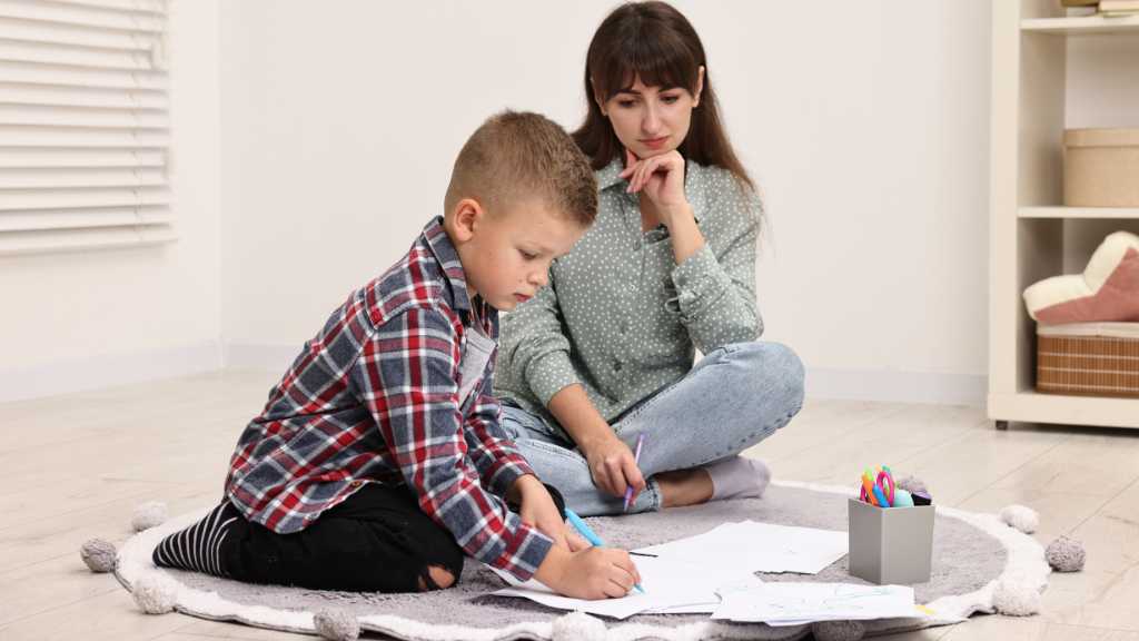 Child receiving supportive guidance during learning activity, illustrating how Level 1 autism replaces the outdated Asperger’s Syndrome label.