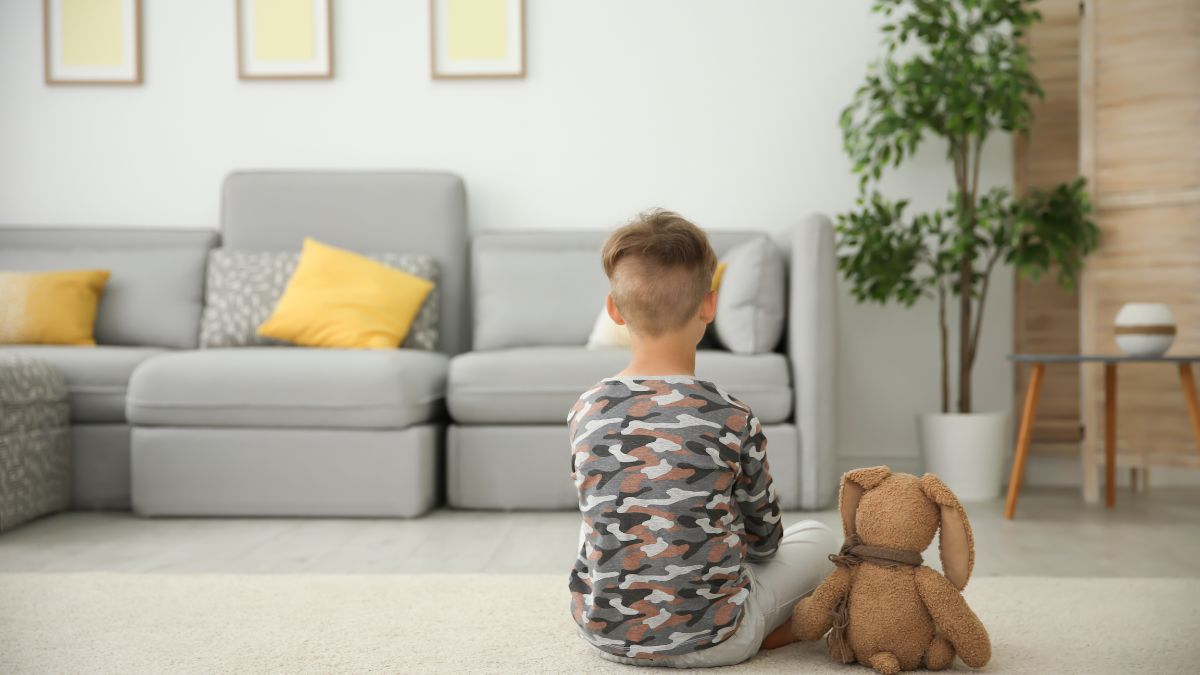 Blog 1 A young child sits alone with his stuffed bunny, backs to the room, separated