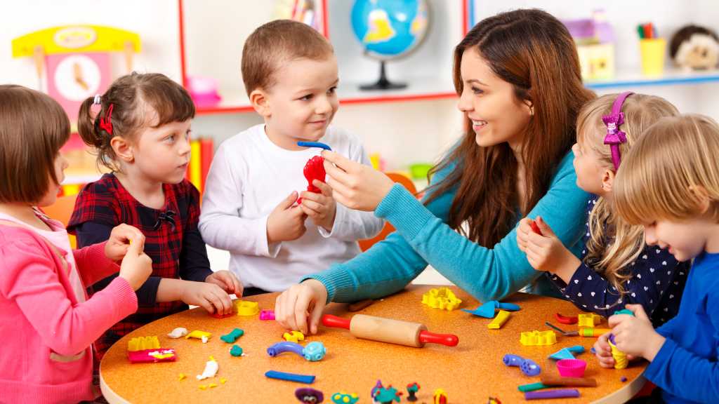 Teacher interacting with young children during playtime, representing early intervention and support that go beyond autism level classifications.