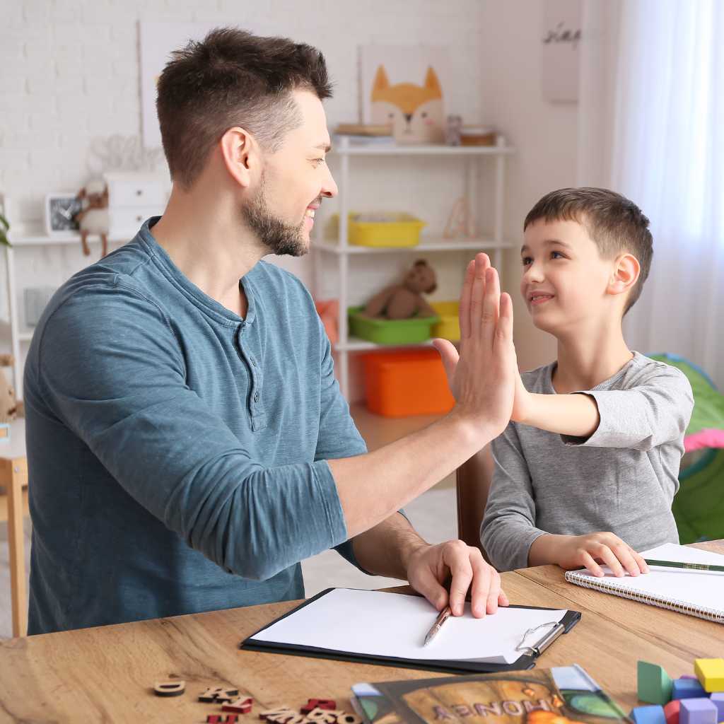 Child giving a high-five to a therapist during an ABA therapy session for Level 1 autism.