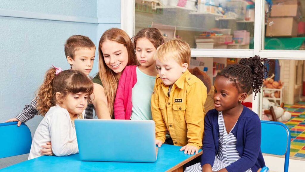 Kids and a teacher gather around a laptop to review the ADDM Community Report