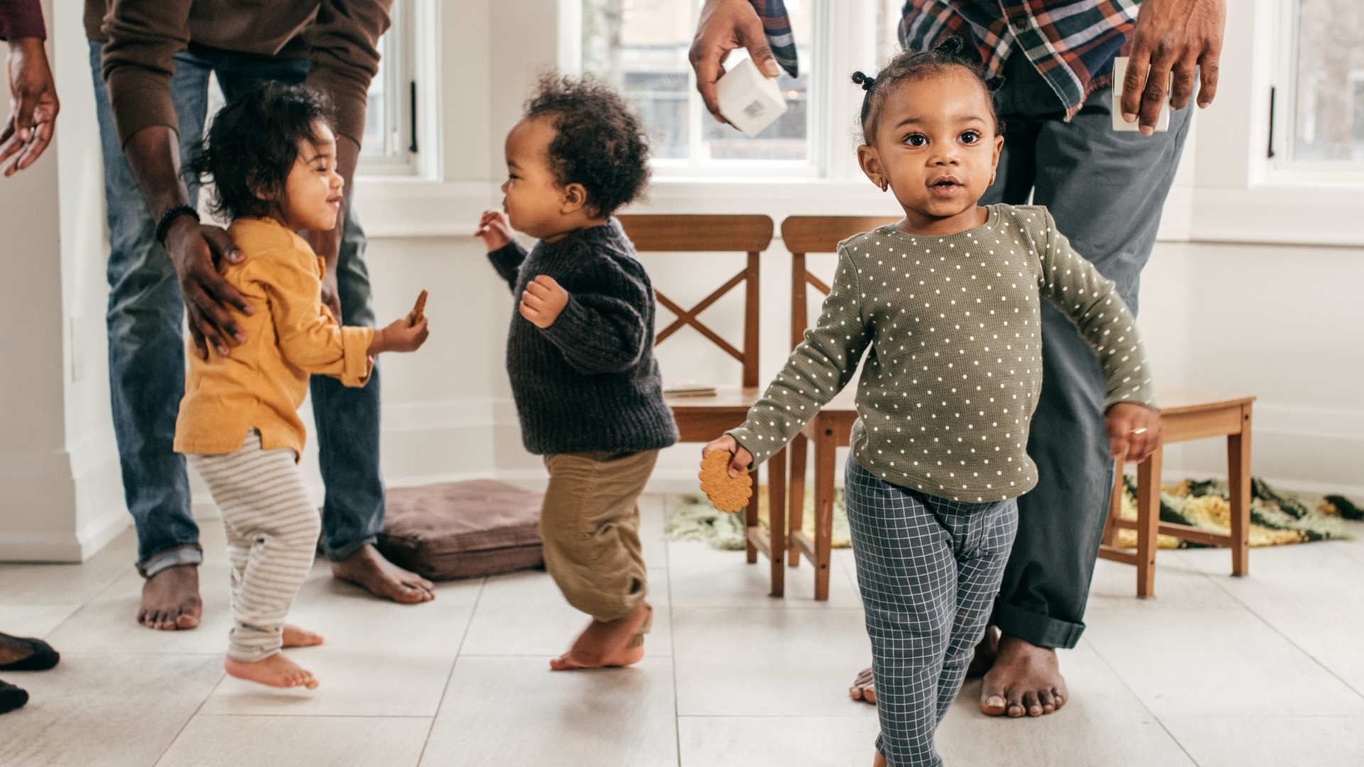 Toddlers move around a space with adults watching over them. The scene hints at moments when a toddler doesn’t respond to their name