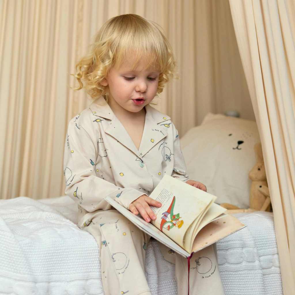 Young child reading a book in bed, representing how ABA therapy supports healthy sleep routines for children with autism.