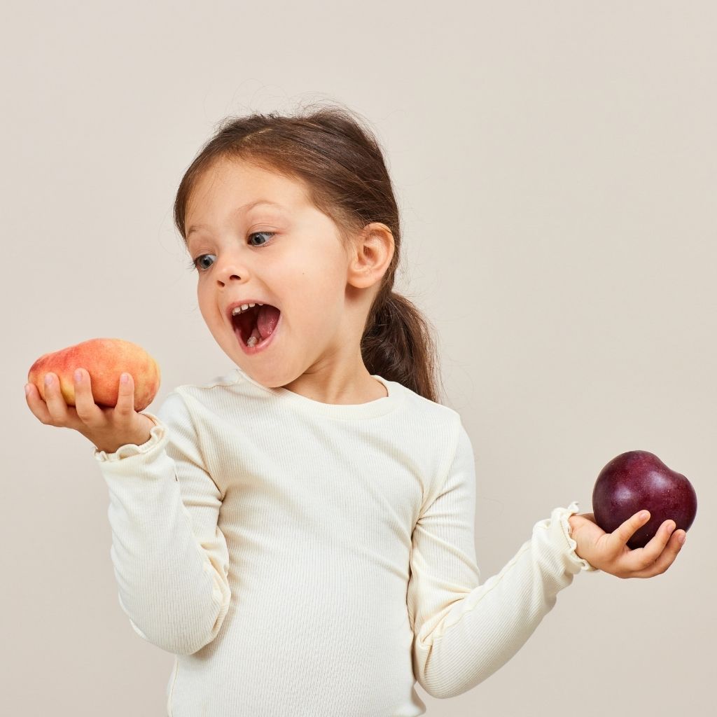 Child choosing between two pieces of fruit during an everyday routine, one of the ABA techniques for parents