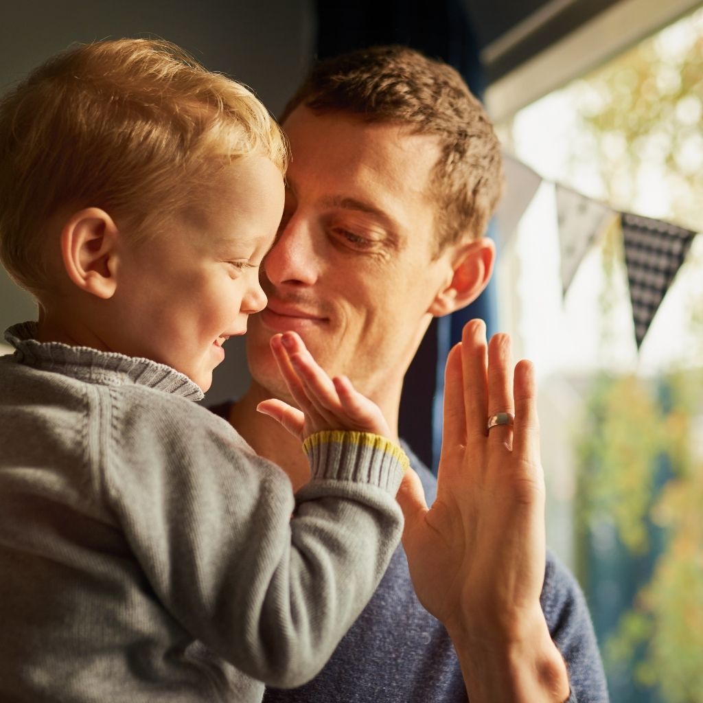 Parent and young child sharing a high-five during an everyday interaction