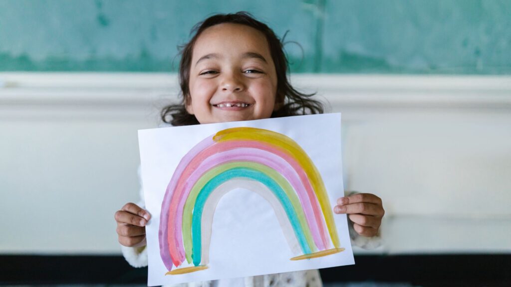 Young child proudly holding up a colorful drawing