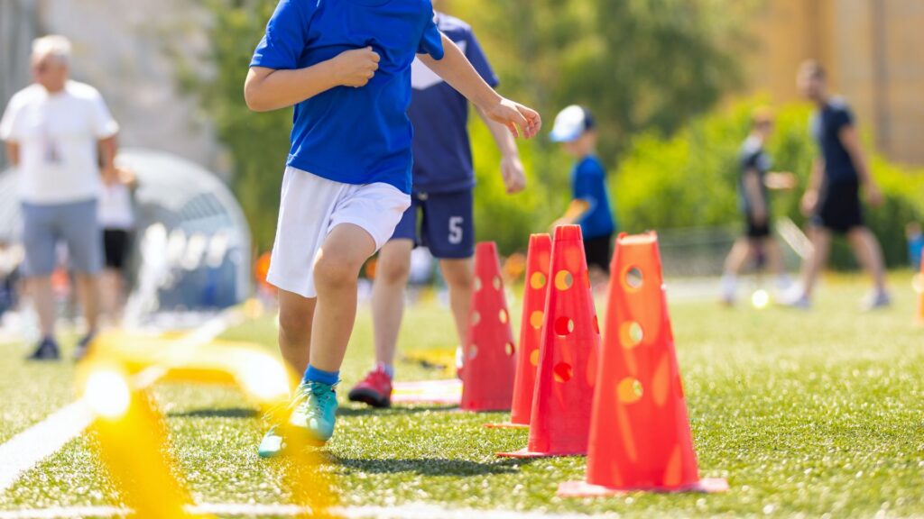 Autism-Friendly Sports for Kids: How to Choose the Right One 5 Child running through an outdoor soccer agility course with orange training cones, illustrating autism-friendly sports that encourage physical activity and coordination.