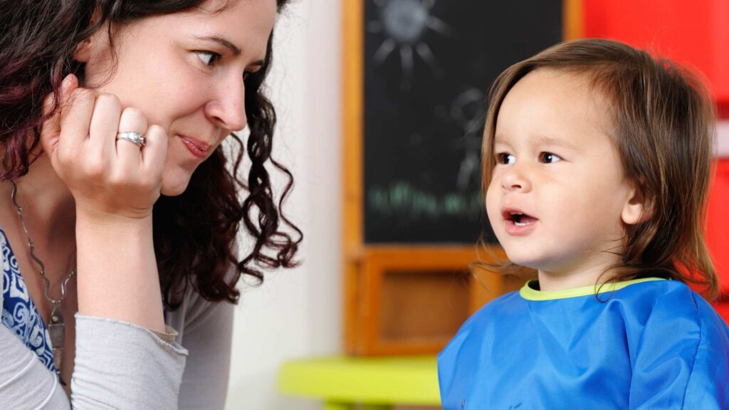 Adult interacting gently with a toddler who is vocalizing