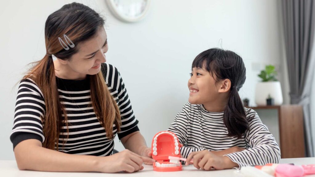 mother teaching daughter child teeth brushing at home