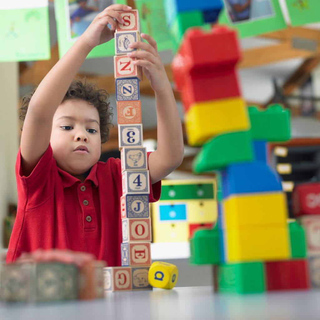 Preschool child carefully stacking alphabet blocks during classroom play
