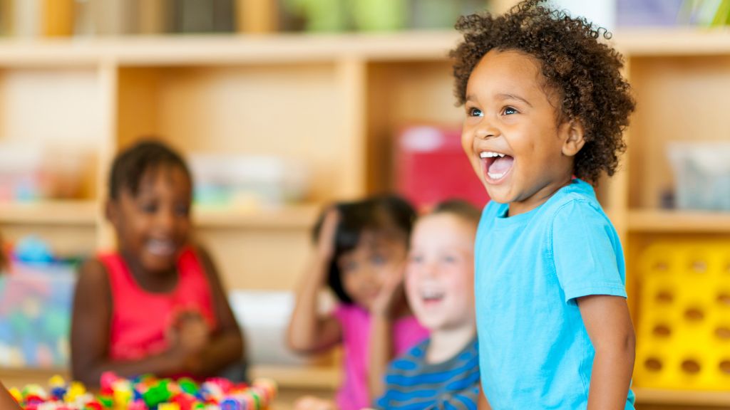 Smiling preschool child participating with classmates in a colorful classroom