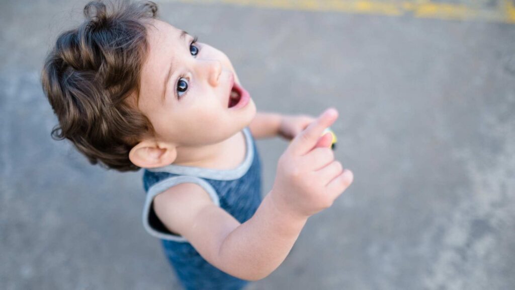 Toddler looking up while pointing, showing early communication behaviors