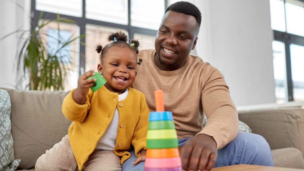 Toddler stacking colorful toys with a caring adult during playtime