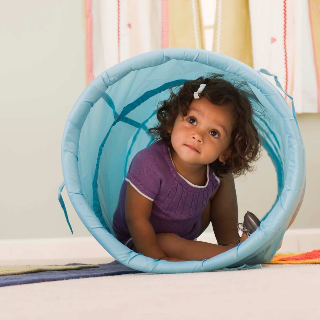 toddler crawling through a blue play tunnel while looking up